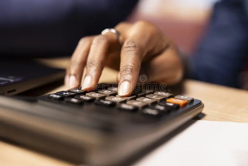 Hands with a ring typing on a calculator over financial documents on a desk