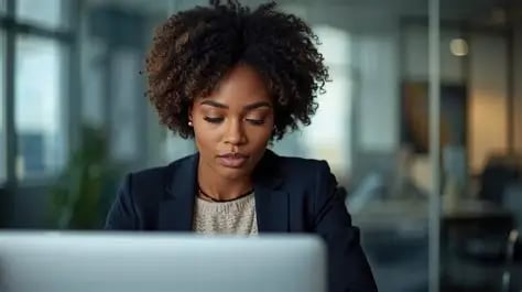 Professional woman with curly hair working on a laptop in a modern office